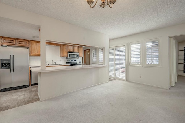 kitchen featuring light carpet, appliances with stainless steel finishes, backsplash, and a textured ceiling