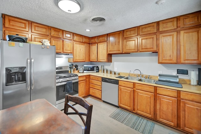 kitchen featuring a textured ceiling, sink, stainless steel appliances, and light hardwood / wood-style flooring