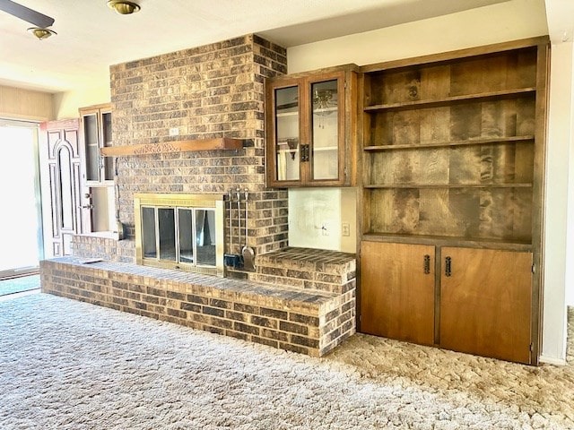 unfurnished living room featuring carpet floors and a brick fireplace