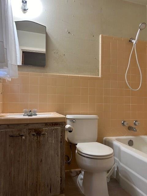 full bathroom with vanity, tiled shower / bath combo, toilet, and tile walls