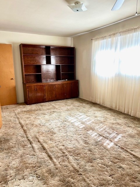 unfurnished living room featuring ceiling fan and carpet floors