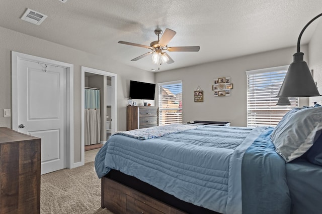 bedroom featuring ceiling fan, light colored carpet, multiple windows, and a textured ceiling