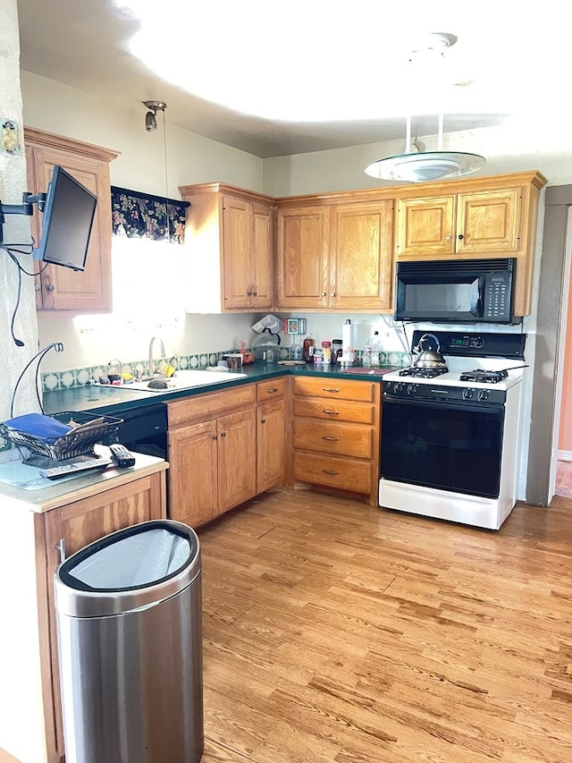 kitchen featuring light hardwood / wood-style floors, sink, white gas range oven, and hanging light fixtures