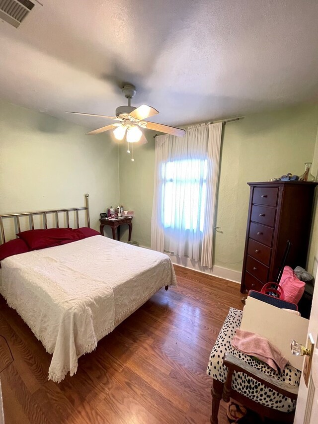 bedroom with dark hardwood / wood-style flooring and ceiling fan