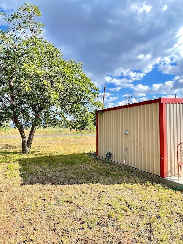 view of outdoor structure featuring a lawn and a rural view