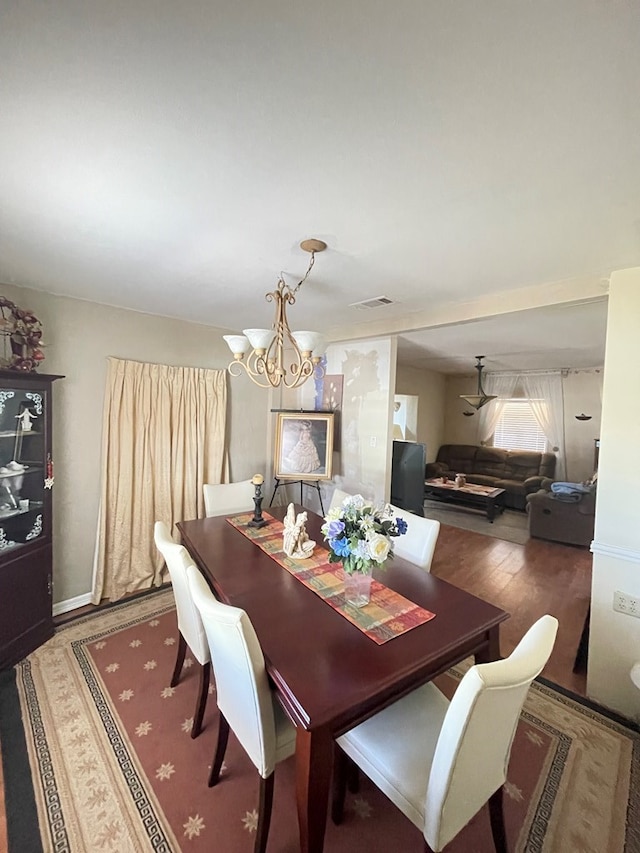 dining area with dark hardwood / wood-style flooring and an inviting chandelier