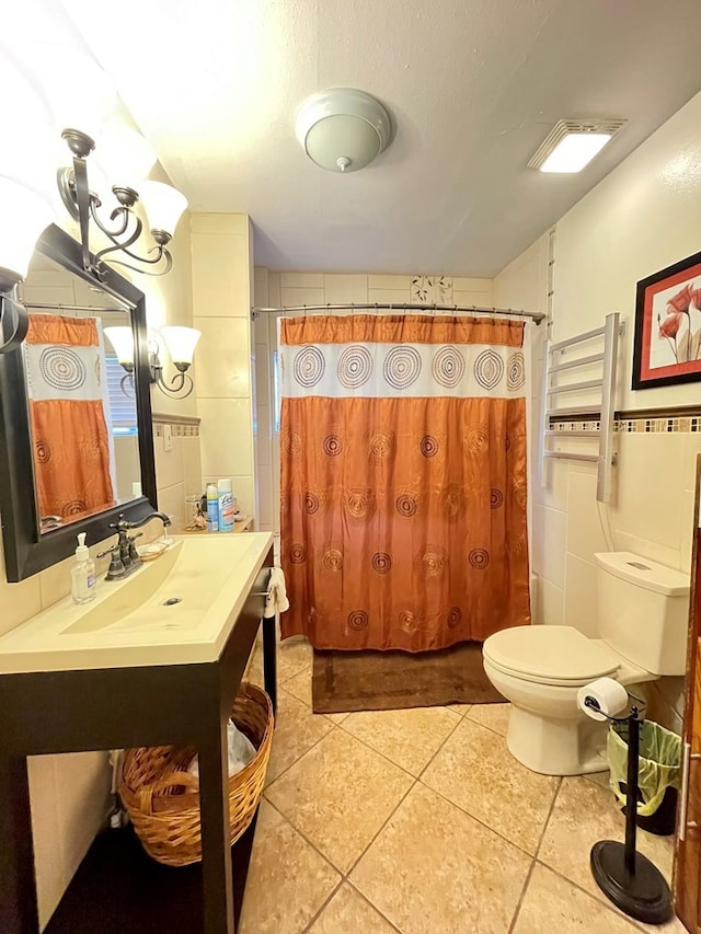 bathroom featuring radiator heating unit, tile patterned floors, toilet, vanity, and tile walls