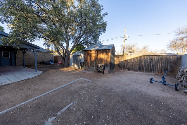 view of yard with a fenced backyard, an outdoor structure, a patio, and a storage unit