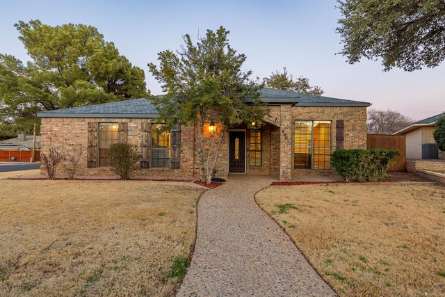 ranch-style house featuring a front yard, fence, and brick siding