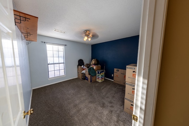 game room with baseboards, visible vents, ceiling fan, dark colored carpet, and a textured ceiling