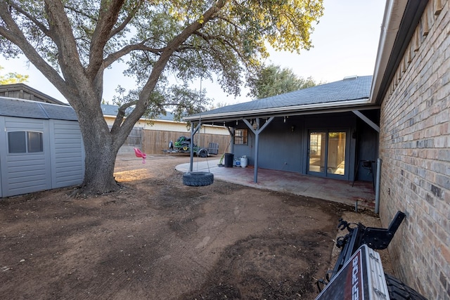 view of yard featuring a storage shed, a patio area, fence, and an outdoor structure