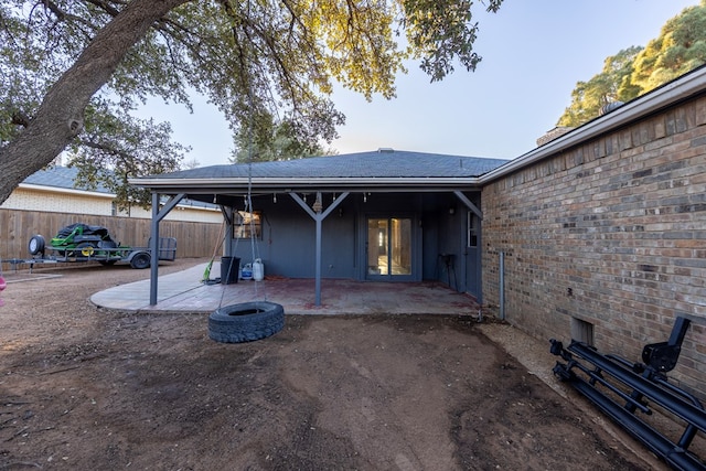 back of property featuring brick siding, fence, and a patio