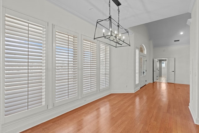 unfurnished dining area featuring ornamental molding, light hardwood / wood-style flooring, and a notable chandelier