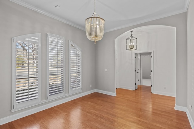 spare room with light wood-type flooring, crown molding, and an inviting chandelier