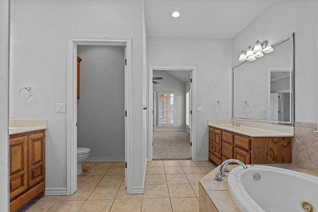 bathroom featuring toilet, tile patterned floors, tiled bath, and vanity