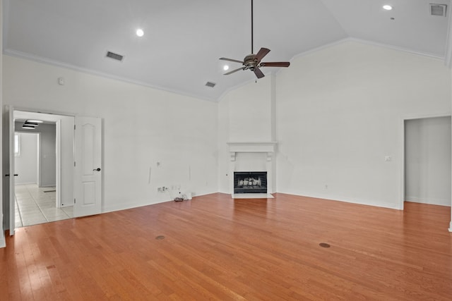 unfurnished living room with lofted ceiling, ceiling fan, a fireplace, light hardwood / wood-style flooring, and ornamental molding