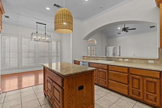 kitchen featuring tasteful backsplash, a kitchen island, sink, hanging light fixtures, and light tile patterned floors