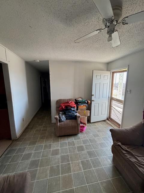 carpeted living room featuring ceiling fan and a textured ceiling