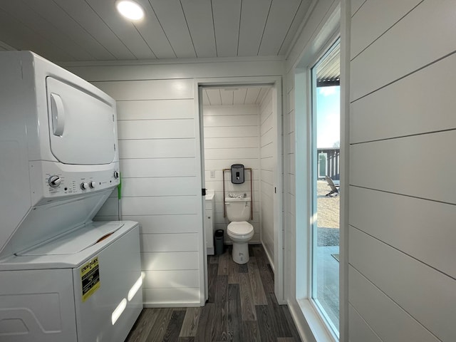 bathroom with hardwood / wood-style floors, stacked washer / dryer, and wooden walls