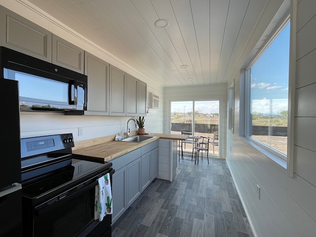 kitchen with sink, dark wood-type flooring, wooden counters, gray cabinets, and black appliances