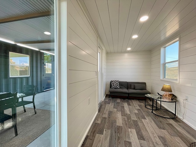 sitting room with plenty of natural light, wood-type flooring, and wooden walls