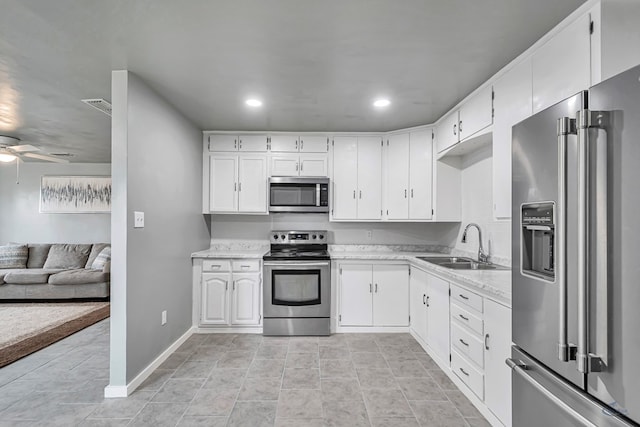 kitchen featuring appliances with stainless steel finishes, ceiling fan, sink, light tile patterned floors, and white cabinetry