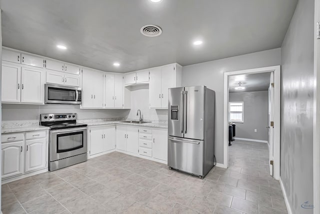 kitchen featuring light stone counters, white cabinetry, sink, and appliances with stainless steel finishes