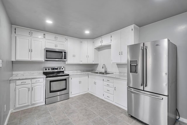 kitchen with white cabinets, appliances with stainless steel finishes, light stone counters, and sink