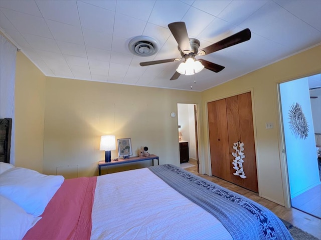 bedroom featuring ceiling fan, ensuite bath, wood-type flooring, and a closet