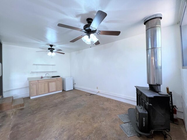 living room with concrete flooring, sink, and a wood stove