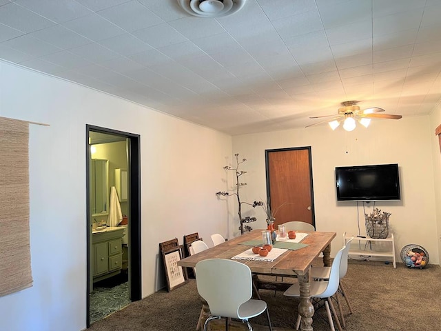 dining space featuring ceiling fan and dark carpet