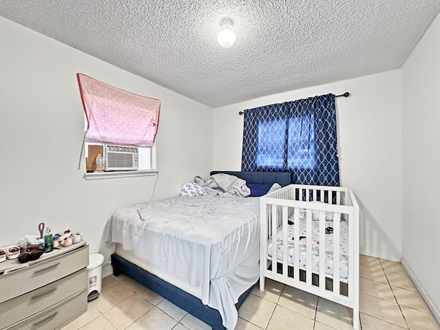 bedroom featuring cooling unit, light tile patterned floors, and a textured ceiling