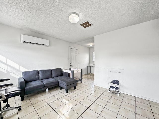 living room featuring a wall unit AC, light tile patterned floors, and a textured ceiling