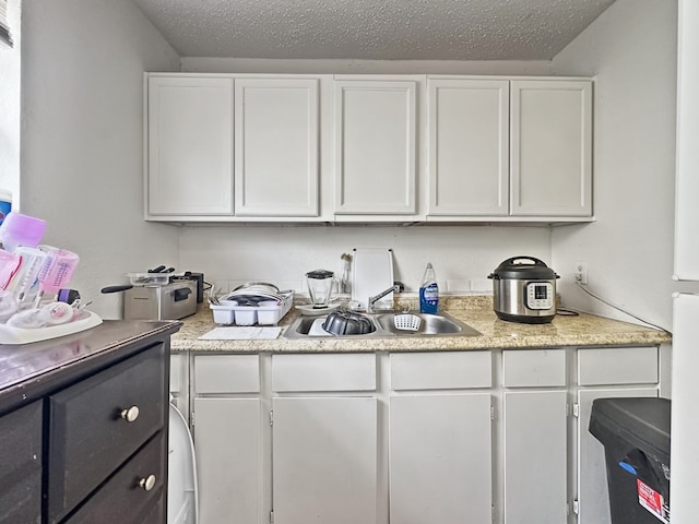 kitchen featuring white cabinetry, sink, and a textured ceiling