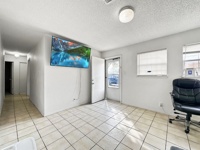 unfurnished office with light tile patterned floors, a healthy amount of sunlight, and a textured ceiling