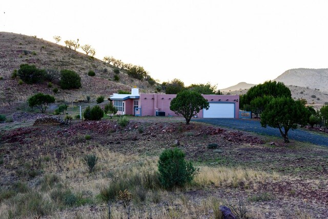 view of yard featuring a mountain view, a garage, and central air condition unit