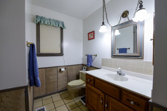 bathroom featuring tile patterned floors, vanity, toilet, and tile walls