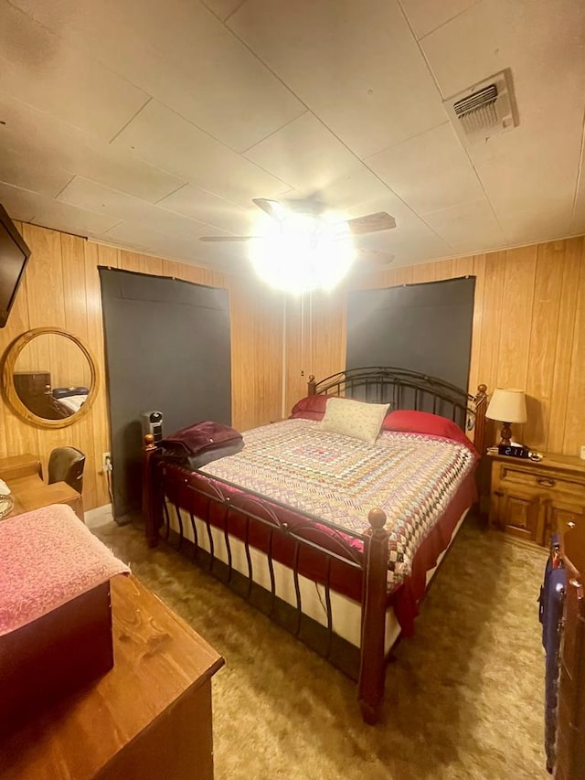 bedroom featuring ceiling fan, dark carpet, and wood walls