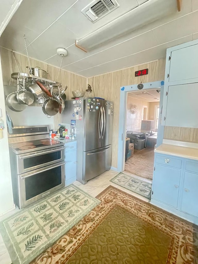 kitchen featuring appliances with stainless steel finishes, wooden walls, and light tile patterned flooring