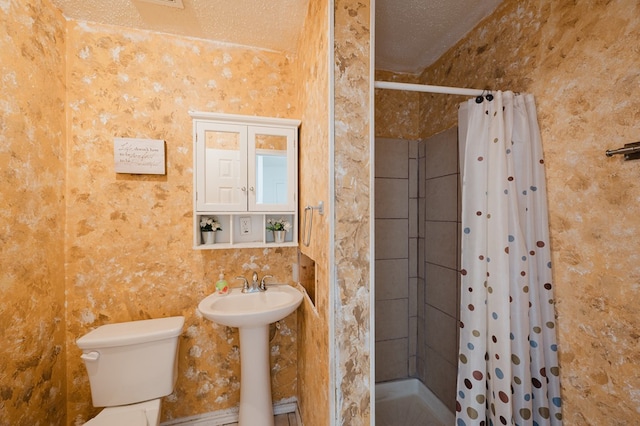 bathroom with sink, curtained shower, toilet, and a textured ceiling