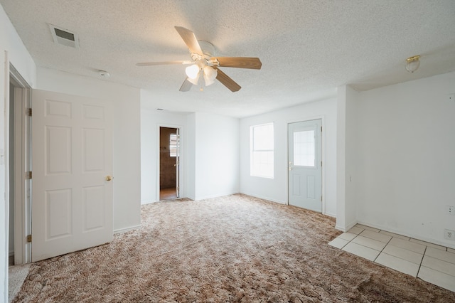 unfurnished room with light carpet, ceiling fan, and a textured ceiling