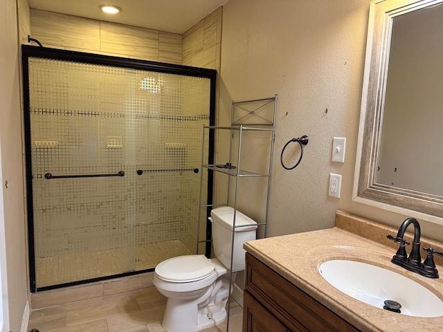 bathroom featuring a shower with door, vanity, and toilet