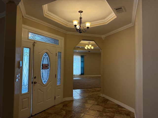 foyer with a chandelier, a tray ceiling, and ornamental molding