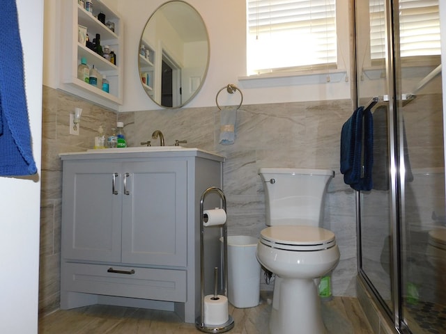 bathroom featuring vanity, hardwood / wood-style flooring, tile walls, toilet, and a shower with shower door