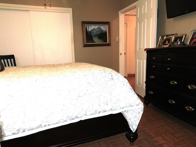 bedroom with dark parquet floors and a closet