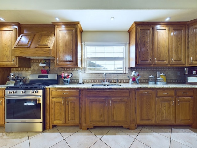 kitchen with light tile patterned floors, custom range hood, backsplash, stainless steel gas stove, and sink