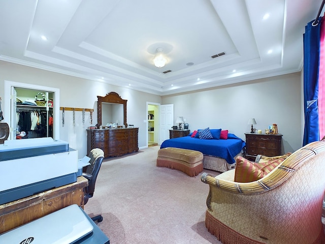 bedroom with a tray ceiling, light carpet, a closet, and a walk in closet