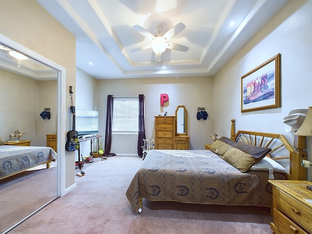 bedroom with a tray ceiling, light carpet, and ceiling fan