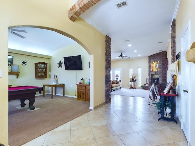 interior space featuring pool table, crown molding, ceiling fan, a fireplace, and light colored carpet