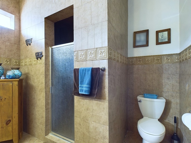 bathroom featuring toilet, tile walls, and an enclosed shower